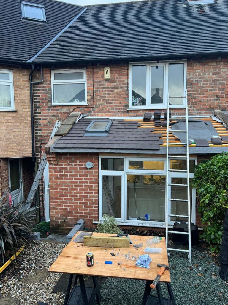 This is a photo of a roof extension that is having new roof tiles installed. This is a photo taken from the roof ridge looking down a tiled pitched roof on to a flat roof. Works carried out by Belper Roofing Repairs